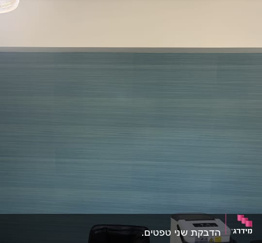 קיר עם טפט כחול ורהיטים בחדר